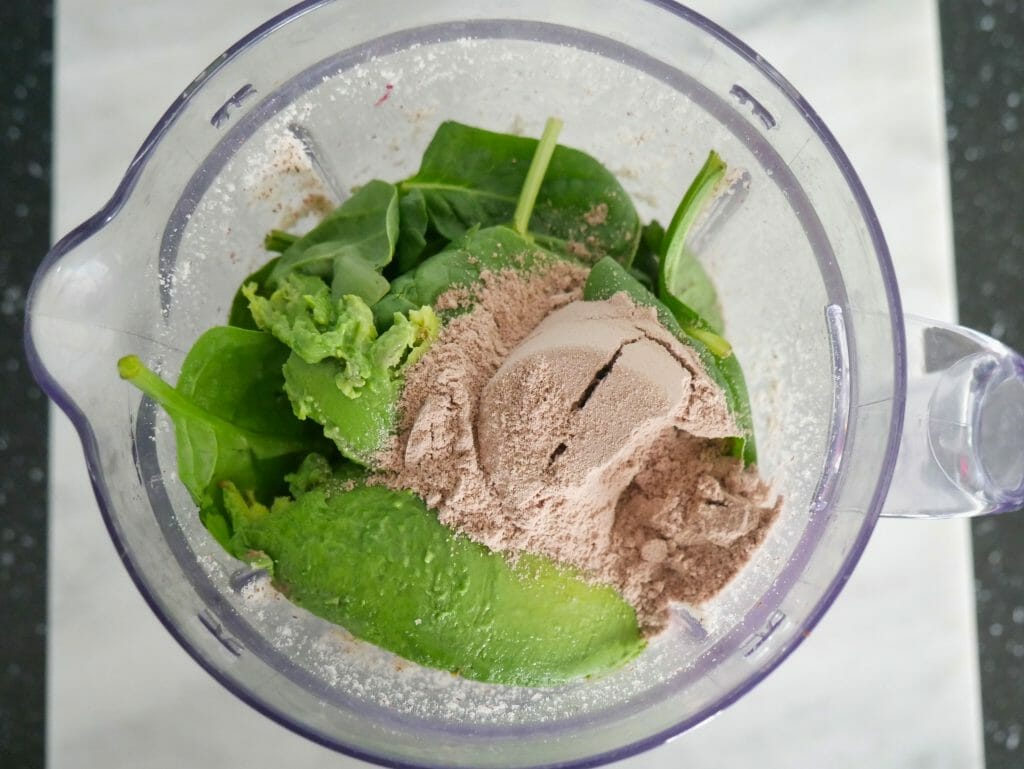 Avocado spinach almonds raspberries and chocolate protein powder in a blender