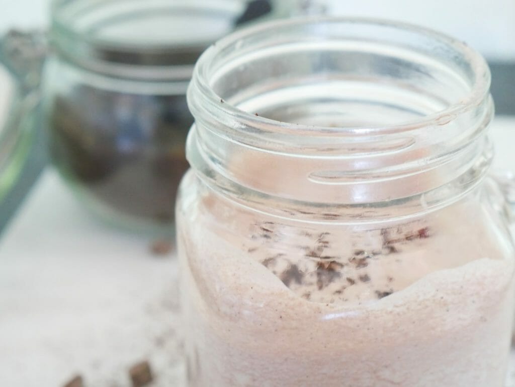 A Keto mocha smoothie with coffee grounds behind it in a glass jar
