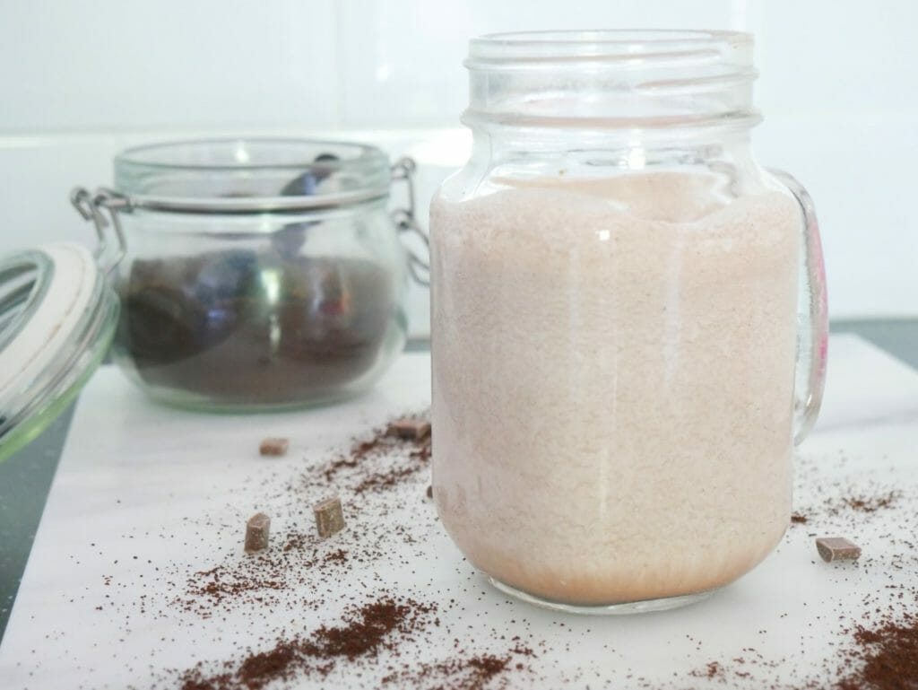 A fat bomb smoothie with coffee grounds in a glass jar behind