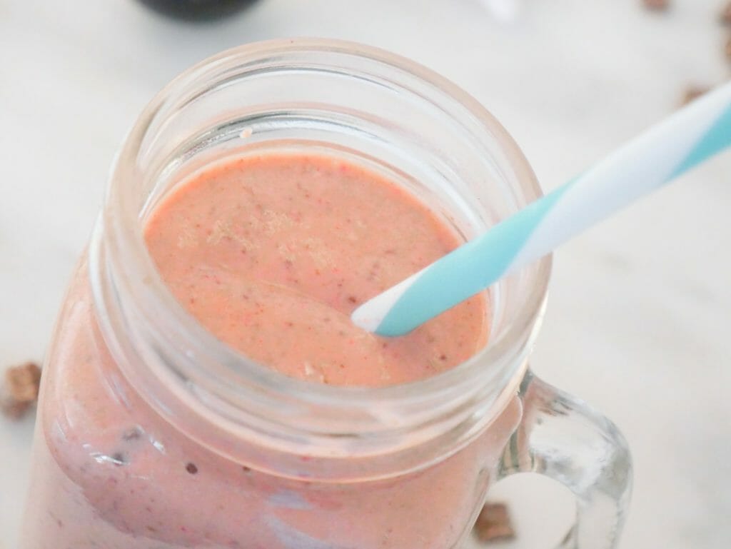 A close-up of the protein berry smoothie seen from above with a blue and white straw