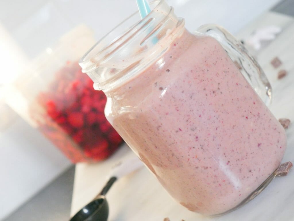 Mixed berry protein smoothie with berries behind and chocolate around