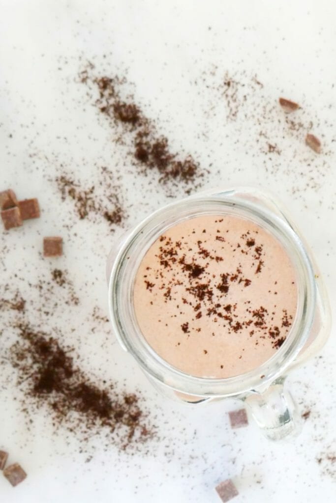 A fat bomb smoothie seen from above with chocolate dusted over it and coffee grounds around it
