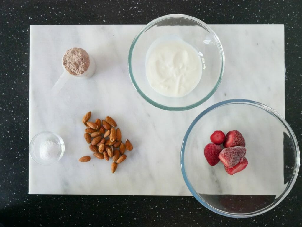 Strawberry chocolate protein shake ingredients on a marble slab