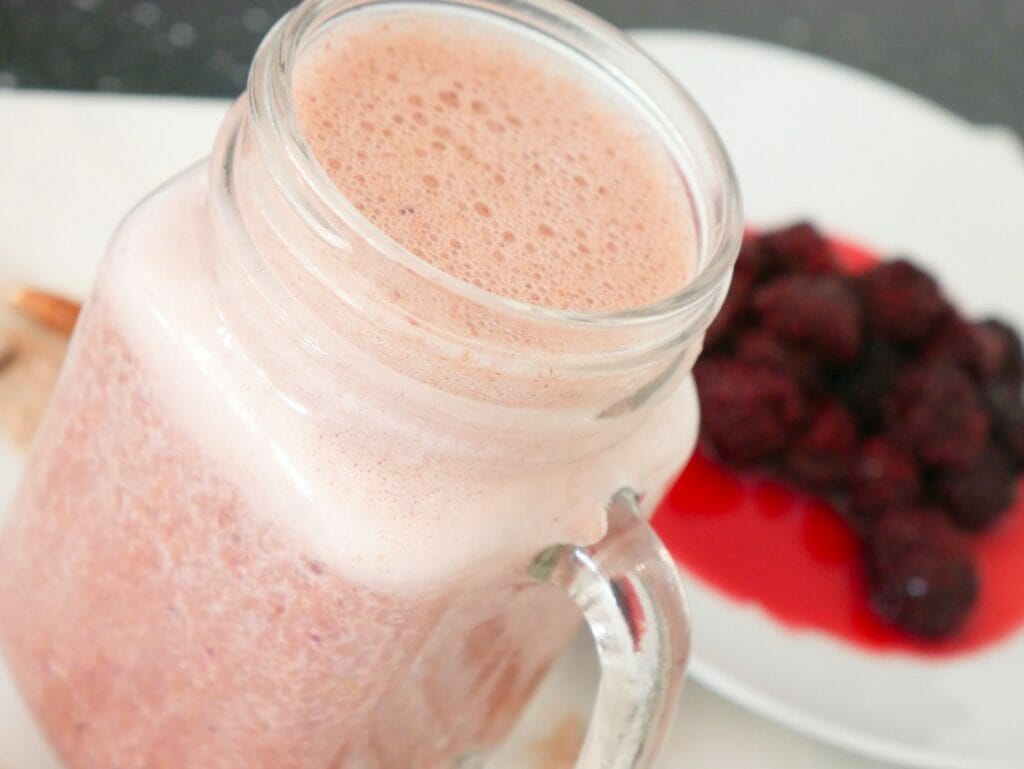 Berry protein shake with blackberries behind