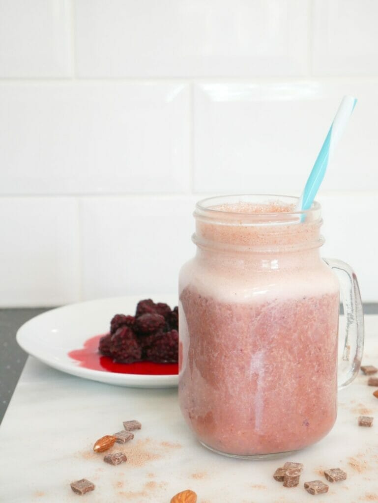 Almond butter and berry protein shake weight gain smoothie with blackberries behind it and almonds and chocolate around