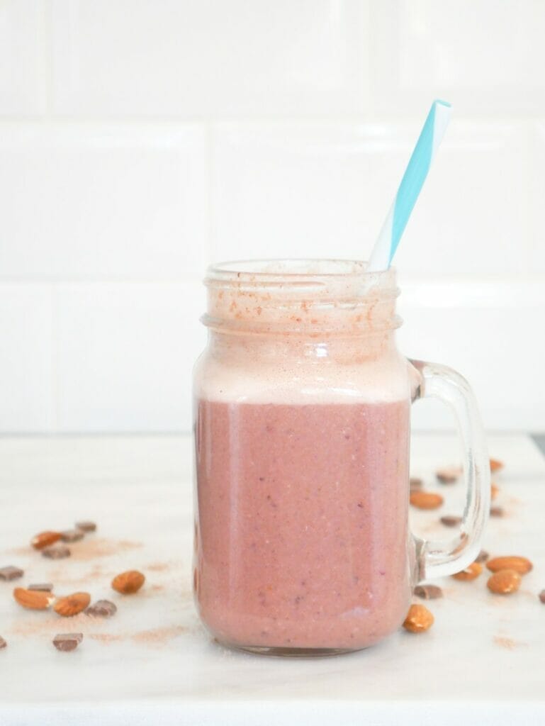 Blackberry smoothie recipe for weight gain with almonds and chocolate around and a blue straw