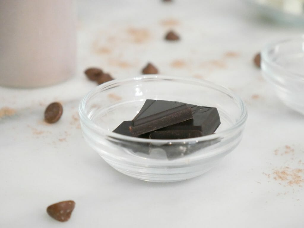 Close-up of chocolate chunks in a small dish with protein behind