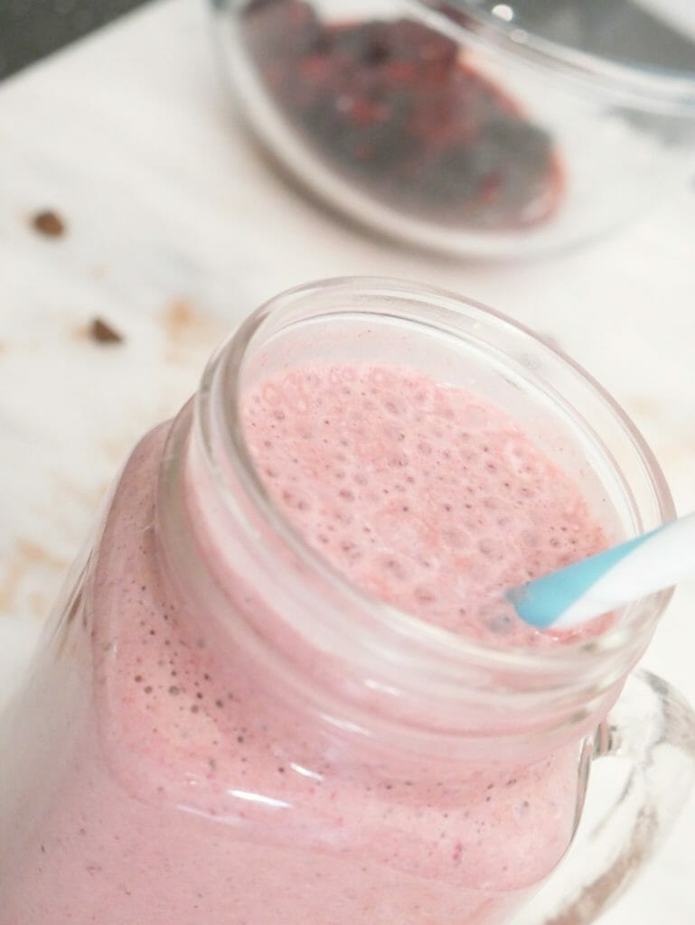 Low carb fruit smoothie made from berries with a blue straw