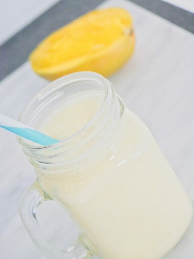 Coconut mango smoothie with blue straw