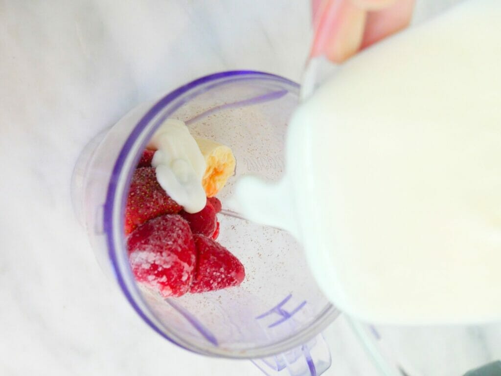 Yogurt going into strawberry banana smoothie