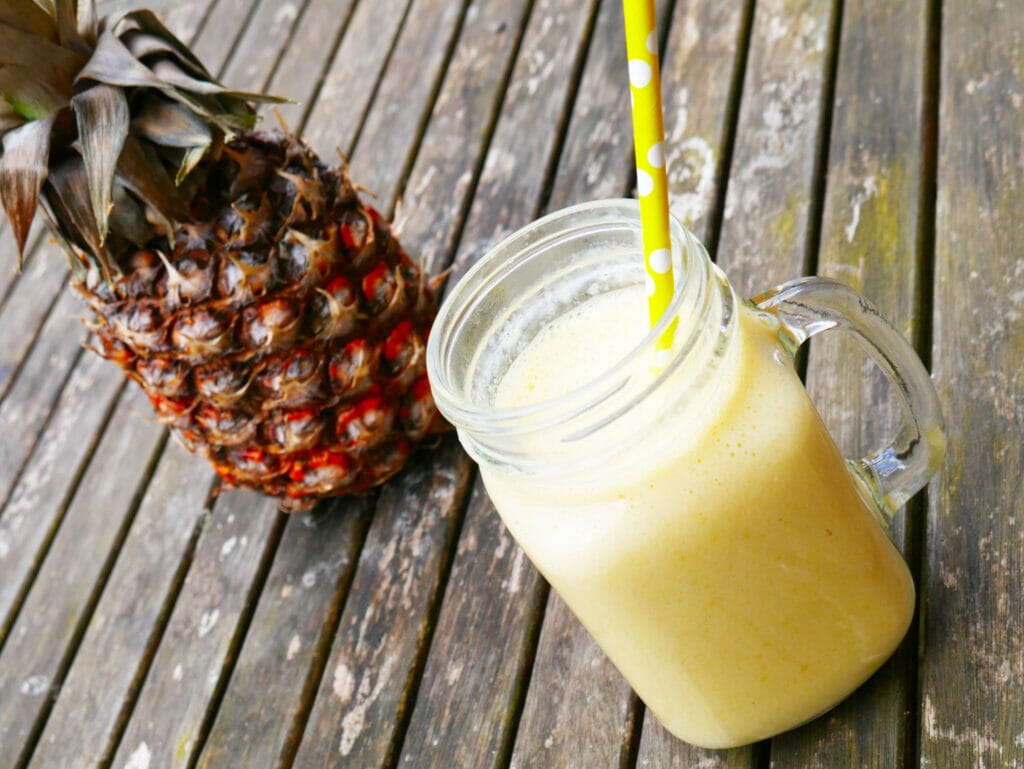 Mango pineapple coconut smoothie with a pineapple behind