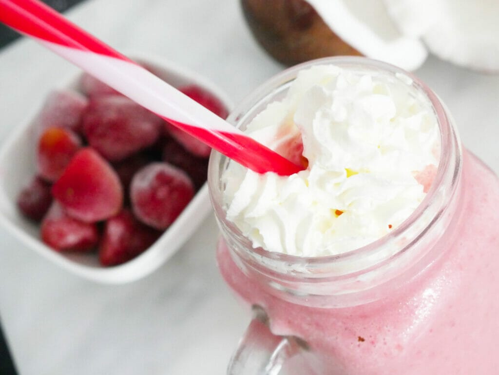 Strawberry coconut milkshake with cream and red straw
